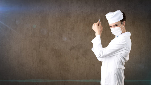 Beautiful medical woman doctor in uniform. Studio painted background. Concept of profitable health care.