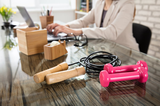 Pink Dumbbells With Skipping Rope On Glass Office Desk