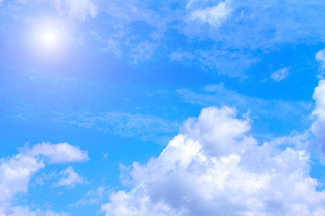 Blue sky background with white clouds and sunshine on sunny summer or spring day.