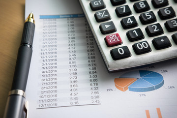 financial charts on the table with laptop, calculator, pen and glasses business concept