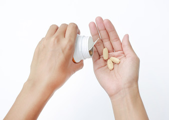 Hand holding yellow pill isolated on white background.