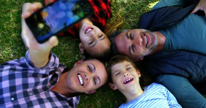 Happy family lying on the grass and taking selfie