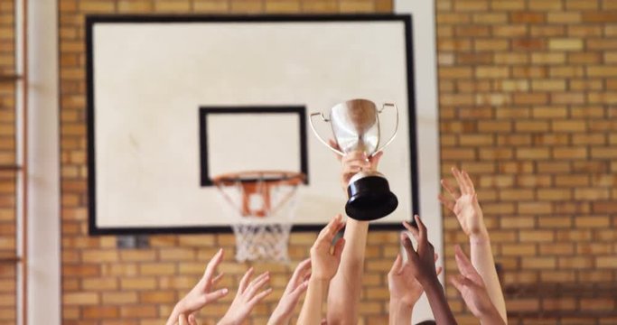 High school kids holding trophy in basketball court