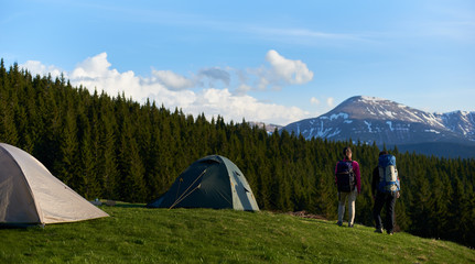 Full length shot of two female hikers with backpacks enjoying stunning view from the top of a hill while camping and hiking in the mountains friendship achievement nature peaceful freedom.