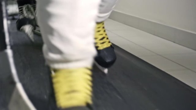 Low-section dolly of legs of hockey players in ice skates walking along rubber floor