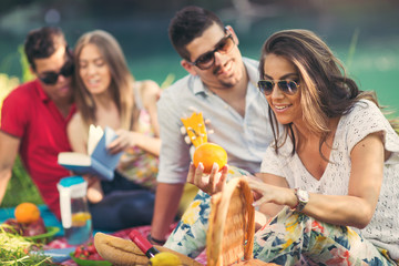 Young people having picnic near the river. Young friends relaxing by the river