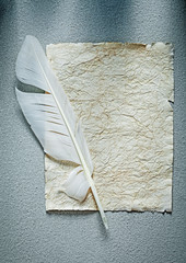 Ancient crumpled paper sheet feather on grey surface