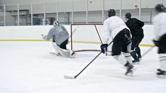 Tracking of ice hockey forward in black uniform pushing player in white gear into boards and stealing puck, then passing it to teammate who scoring tricky goal