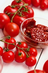 Several common types of tomatoes on white wooden table. Cherry, regular,canned peeled,sun dried in olive oil.