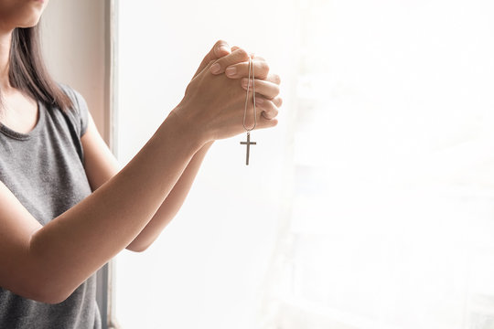 Beautiful calm girl with closed eyes praying on holy bible.