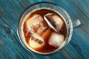 Glass cup of cold brew coffee on wooden tray