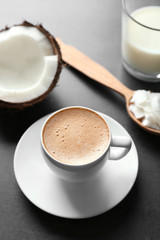 Cup of tasty coconut coffee, nut and spoon with butter on table