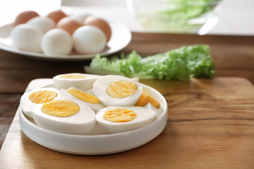 Ceramic plate with hard boiled eggs on wooden surface. Nutrition concept