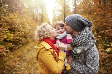 Joyful scene of parents kissing daughter