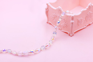 Pink box and crystal necklace and on pink wallpaper. Make up and beauty concept.