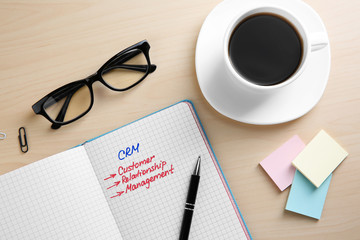 Copybook, eyeglasses and cup of coffee on wooden table. Management concept