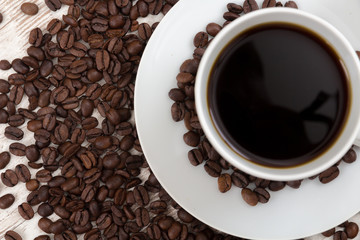 Obraz premium Kaffeetasse mit Kaffeebohnen auf weißem holztisch