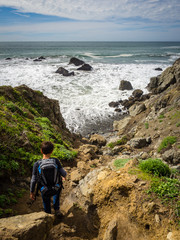 10 year old boy hiking on California Coast down to beach with crashing waves, Pirates Cove Trail, Marin Headlands, Golden Gate National Recreation Area, California, United States