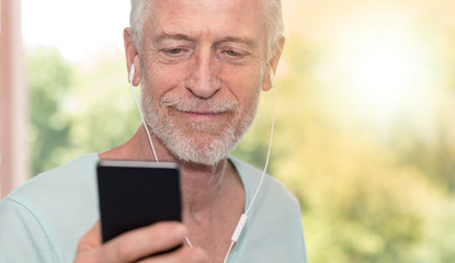 Portrait of mature man listening music with earphones, light effect