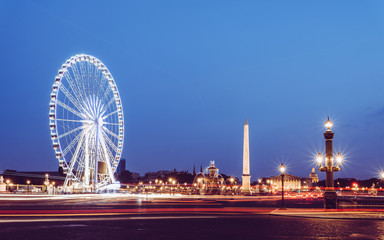 Traffic on place de La Concorde at night in Paris with view on the ferris wheel, the obelisk and National Assembly building