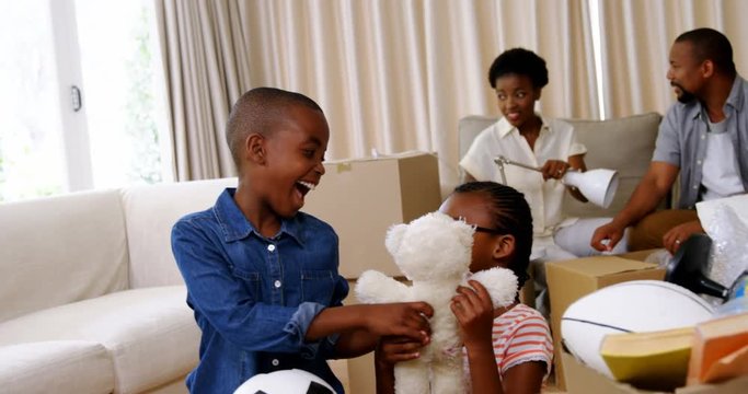 Parents and kids unboxing cardboard boxes in living room
