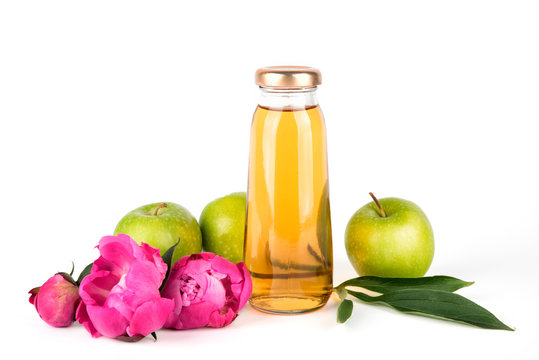 Apple golden juice in bottle. Fruit  soft drink in a glass bottles isolated on white background. Pink flowers peonies
