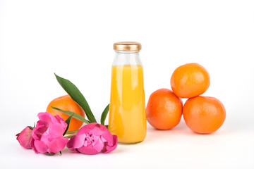Orange fresh juice in bottles. Fruit and vegetable soft drink in a glass bottles isolated on white background. Pink flowers peonies