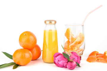 Orange fresh juice in bottles. Fruit and vegetable soft drink in a bottle isolated on white background. Glass with orange slice and straw. Pink flowers peonies