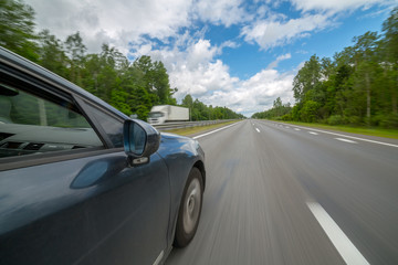 The car moves at high speed on highway at the sunny summer day.