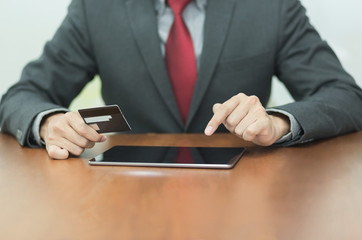 Businessman using tablet and credit card for online shopping or banking.