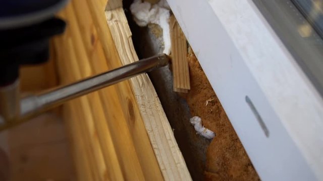 Nozzle of construction gun fills space under window frame by polyurethane foam or with mounting foam.