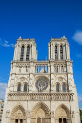 Fototapeta na wymiar Notre Dame de Paris central main facade, national monument cathedral of France. French Gothic architecture. Sunny blue cloudy sky.