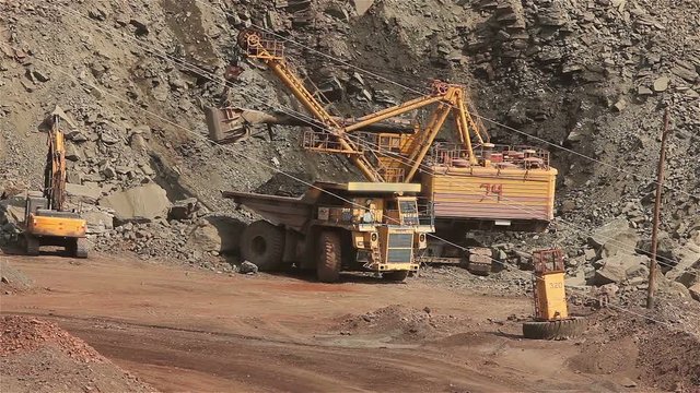 The excavator and dumper in the quarry, Large yellow excavator loaded ore into a dumper, Industrial exterior