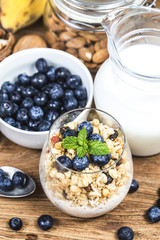 Healthy breakfast: oat granola with yogurt and fresh blueberries on wooden background