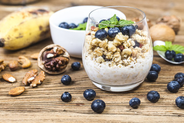 Healthy breakfast: oat granola with yogurt and fresh blueberries on wooden background