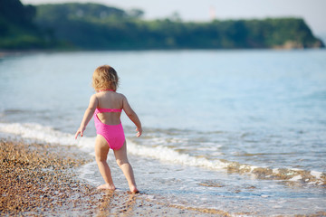 The little girl runs on the beach at the seashore