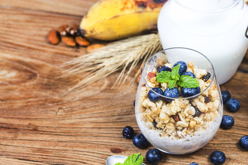 Healthy breakfast: oat granola with yogurt and fresh blueberries on wooden background