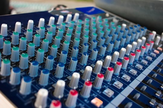 Side closeup of a mixing console with cords. Audio mixer.