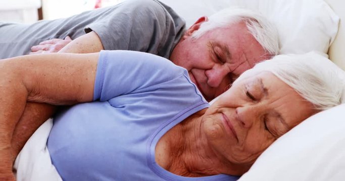 Senior couple sleeping on bed in bedroom