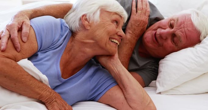 Happy senior couple interacting with each other on bed 