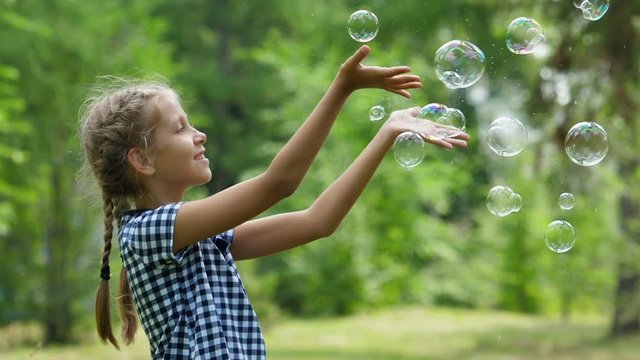 Little girls playing with soap bubbles outdoor. Slow motion.
