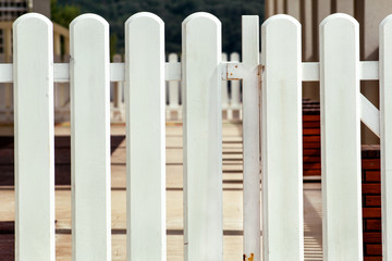 Fototapeta premium White wooden decorative fence isolated. Wooden plank panel background texture. Landscape architecture ideas, details, creative wallpaper. Traditional classic vintage design white wooden fence.