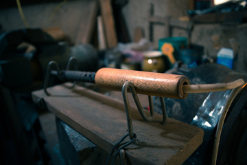 Old soldering iron in the workshop on a steel table.