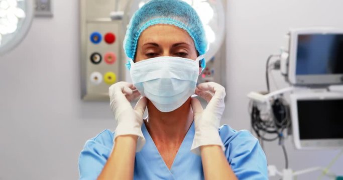 Female nurse tying surgical mask in operation theater