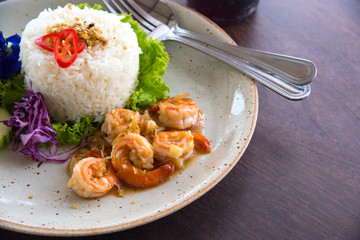 Close up tasty fried pink shrimps cooked with garlic or prawns seasoned with olive oil and herbs served as rice cooked a seafood starter on plate for lunch, Thai Food

