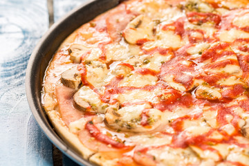 Closeup macro fresh baked round pizza with cheese ham tomato sauce mushrooms