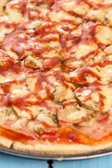 Closeup macro fresh baked round pizza with cheese ham tomato sauce mushrooms