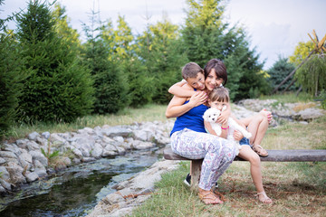 Happy family portrait in nature next to a stream on summer day