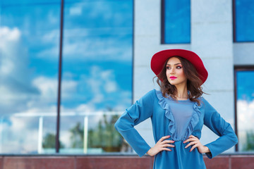 Young woman in red hat, posing in blue dress