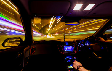 Light trails from inside car, blurred street lights, hand on the wheel and gear